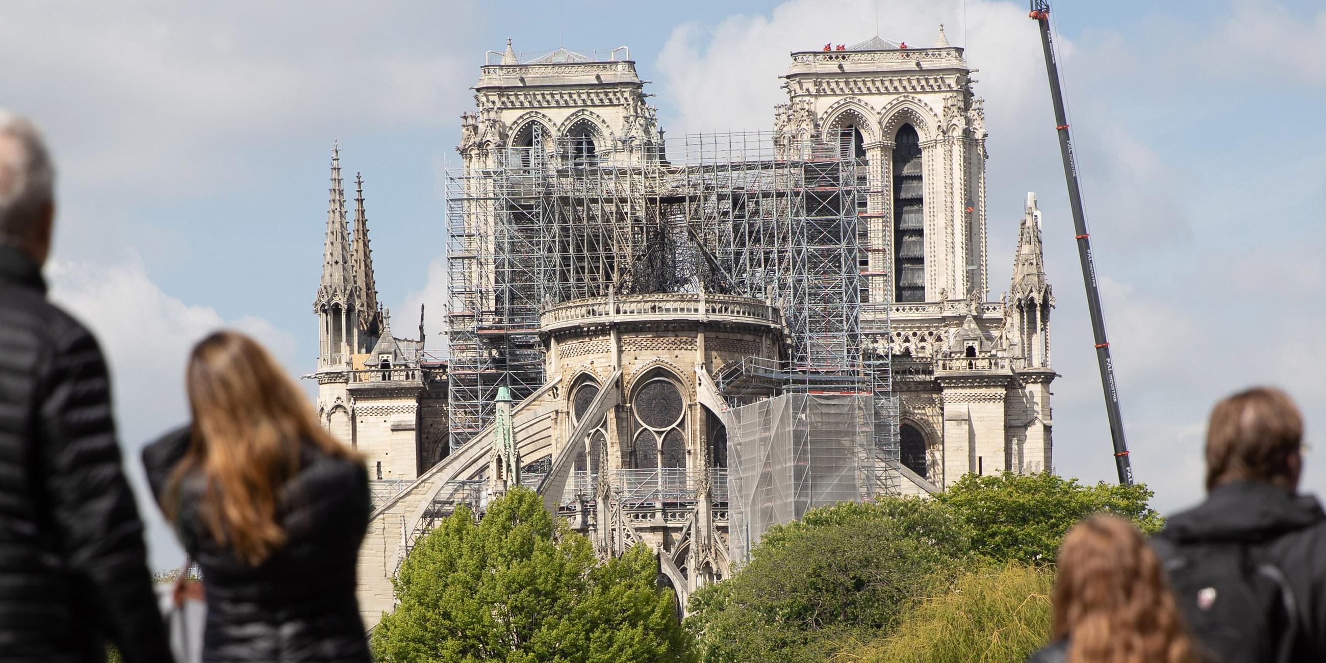 Paris: Ein Kran steht neben der Pariser Kathedrale Notre-Dame, die von Besuchern der Stadt betrachtet wird.