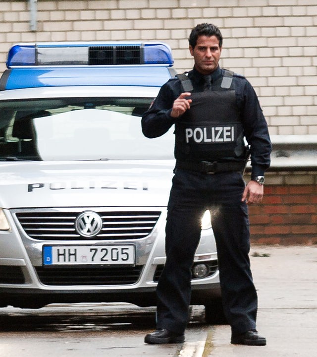 "Notruf Hafenkante - Recht und Gerechtigkeit": Tarik (Serhat Cokgezen) steht mit vorgehaltener Waffe, einsatzbereit vor dem Polizeiwagen.
