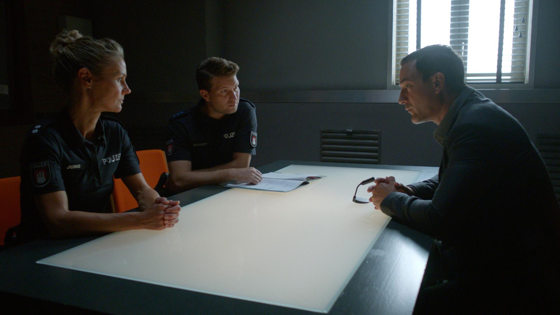 Die Polizistin Franzi Jung (Rhea Harder-Vennewald) und ihr Kollege Nick Brandt (Raúl Richter) sitzen nebeneinander an einem Tisch. Ihnen gegenüber sitzt Peter Schwartz (Sönke Möhring). Franzi und Nick sehen Schwartz an, er blickt zu Franzi.