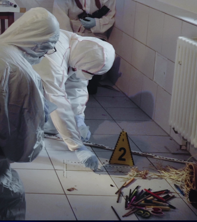 Zwei Personen der Spurensicherung in weißen Einmalanzügen und mit blauen Latexhandschuhen sichern Spuren in einem gekachelten Raum am Boden. Ein gelbschwarzes dreieckiges Aufstellschild mit der schwarzen Ziffer 2 steht im Hintergrund. Rechts im Bild ein Heizkörper. Am Boden Stifte. Links daneben: Lichtschematische Darstellung eines Fingerabdrucks.