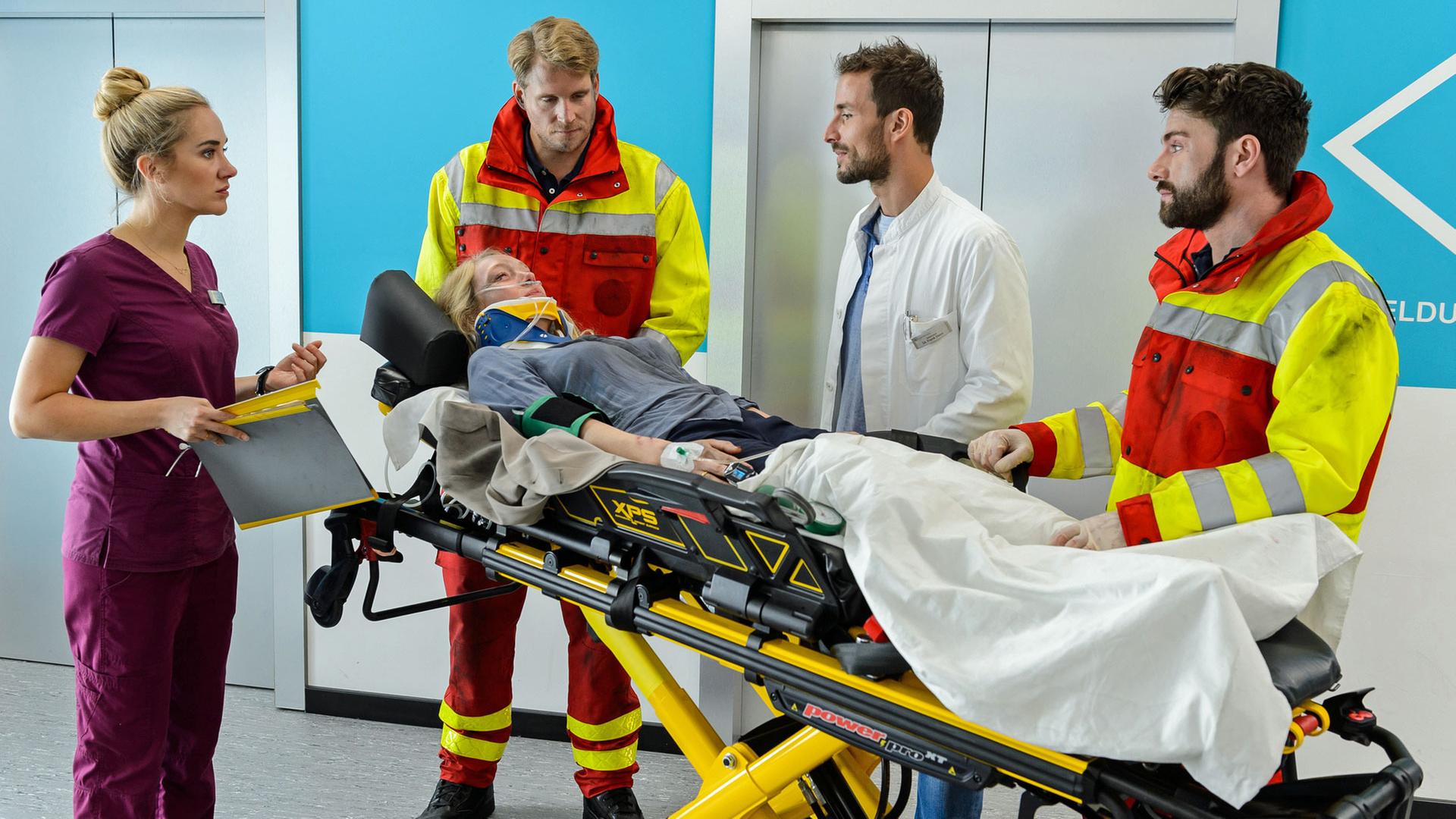 "Bettys Diagnose - Nur ein Spiel": Betty Weiss (Annina Hellenthal)nimmt von den Sanitätern Oliver Weiss (Alexander Koll) und Jens Liebertz (Florian Jahr) mit Dr. Frank Stern (Max Alberti) die verletzte Patientin Anne Bechstein (Katharina Heyer) in Empfang.
