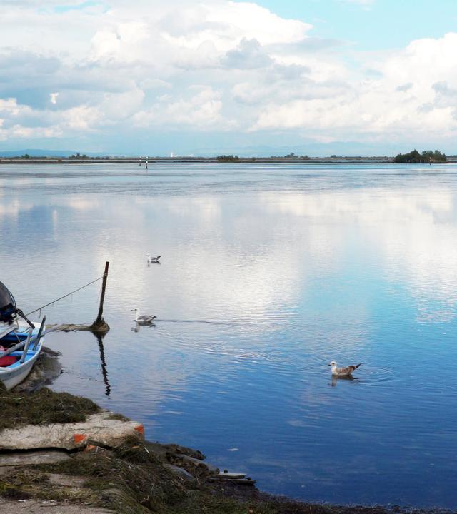 ein boot liegt am wasser vor einem blauen himmel