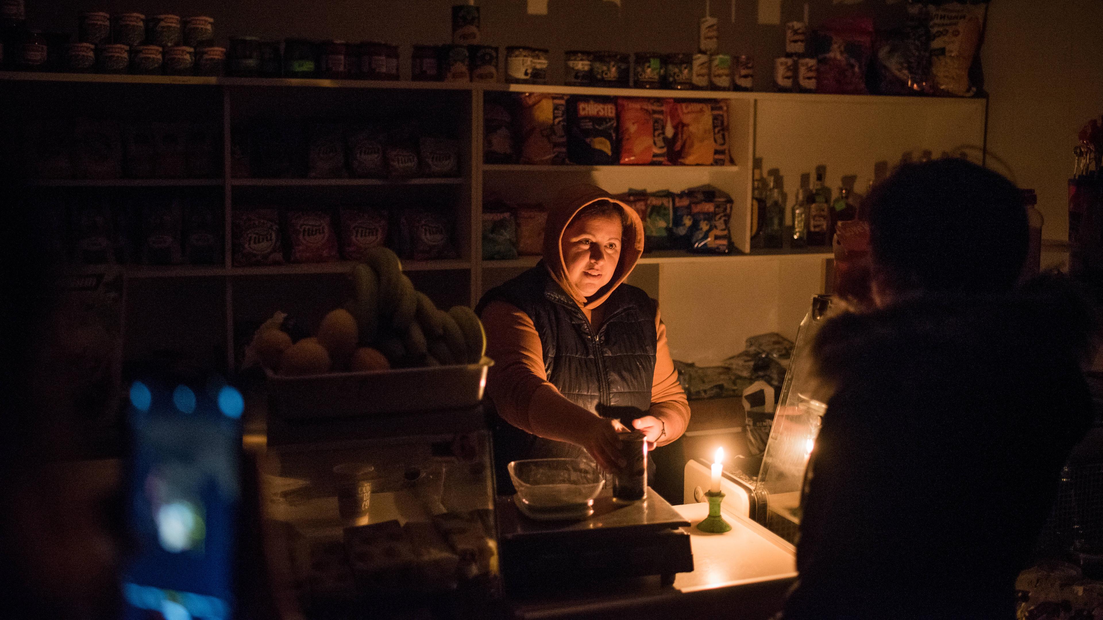 Lebensmittelhändler bedient Kunden bei Kerzenlicht