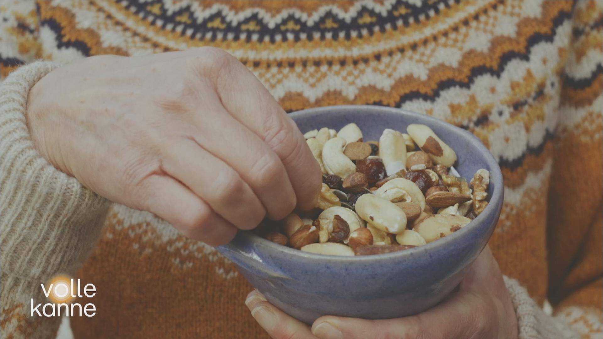 Jemand greift in eine Schale mit Studentenfutter
