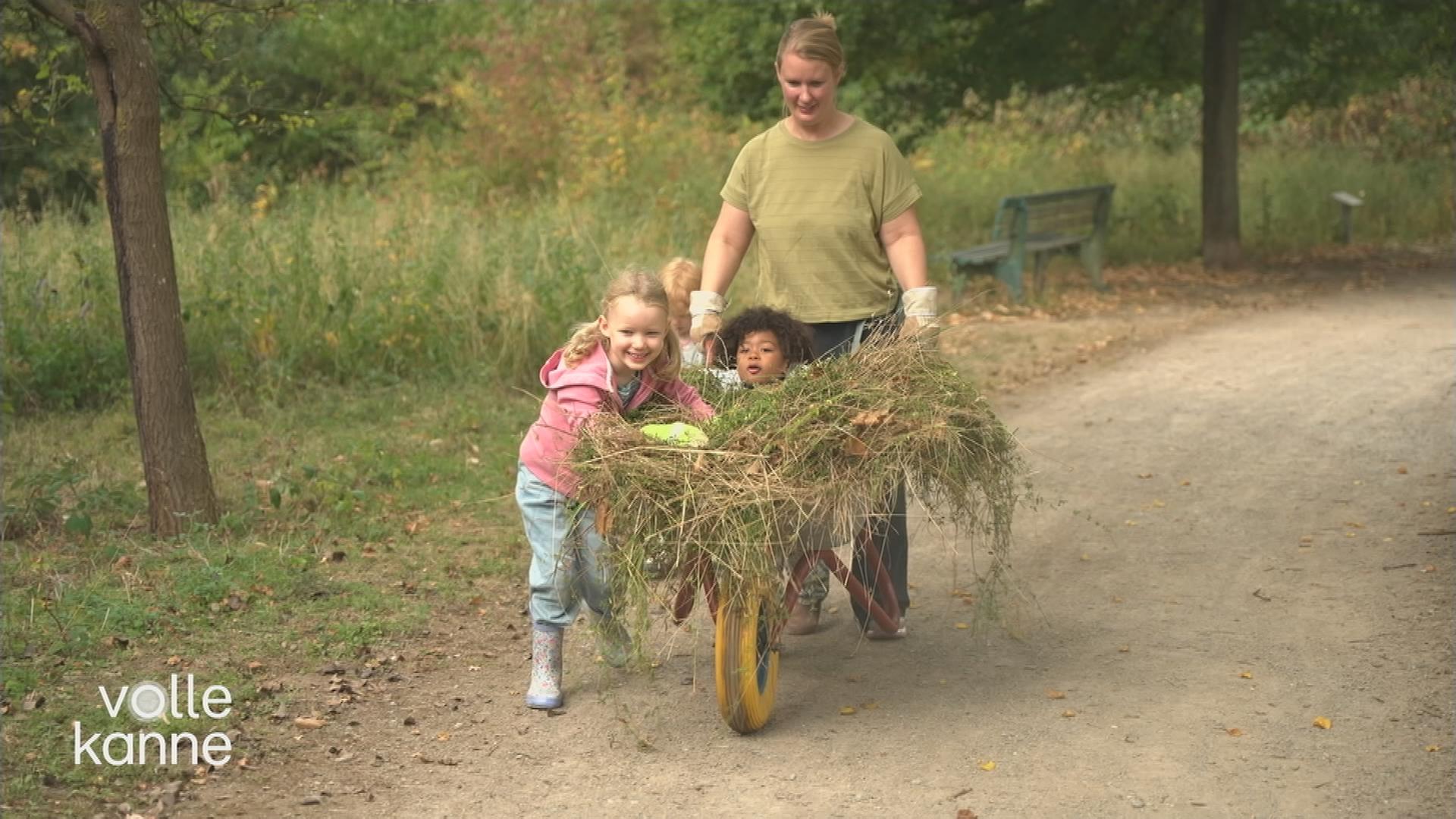 Eine Frau schiebt eine Schubkarre zusammen mit Kindern.