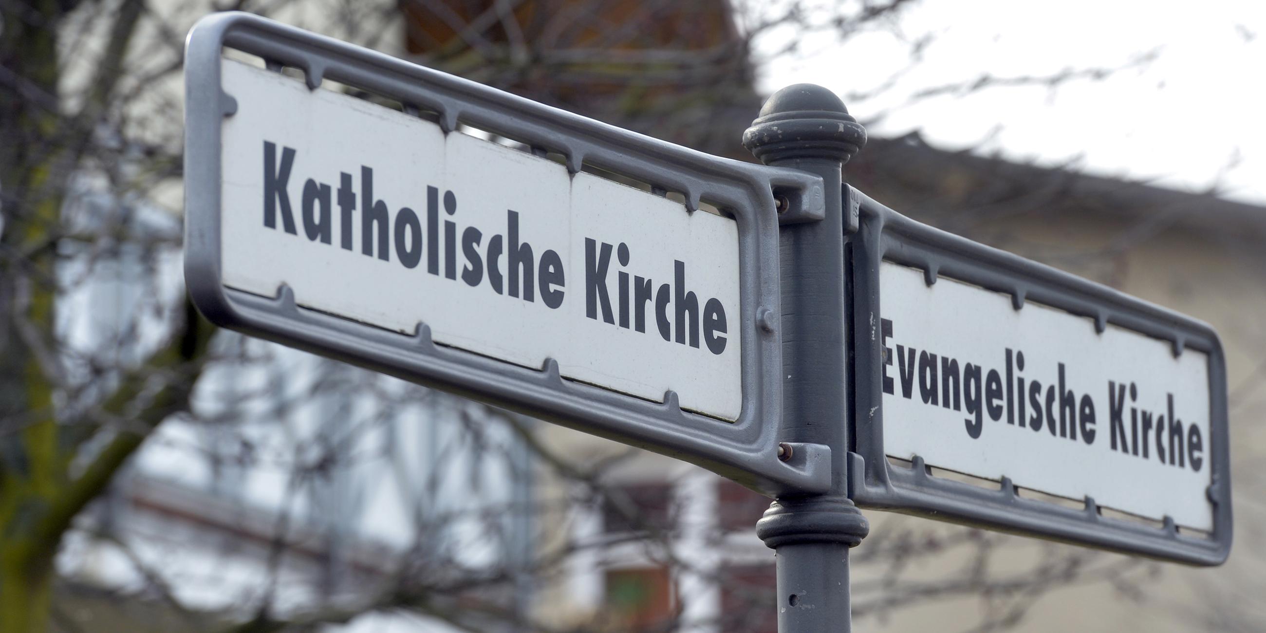 "Evangelische / Katholische Kirche" - ein Wegweiser in Kühlungsborn zeigt in die beiden Richtungen, in denen sich die verschiedenen Kirchen befinden