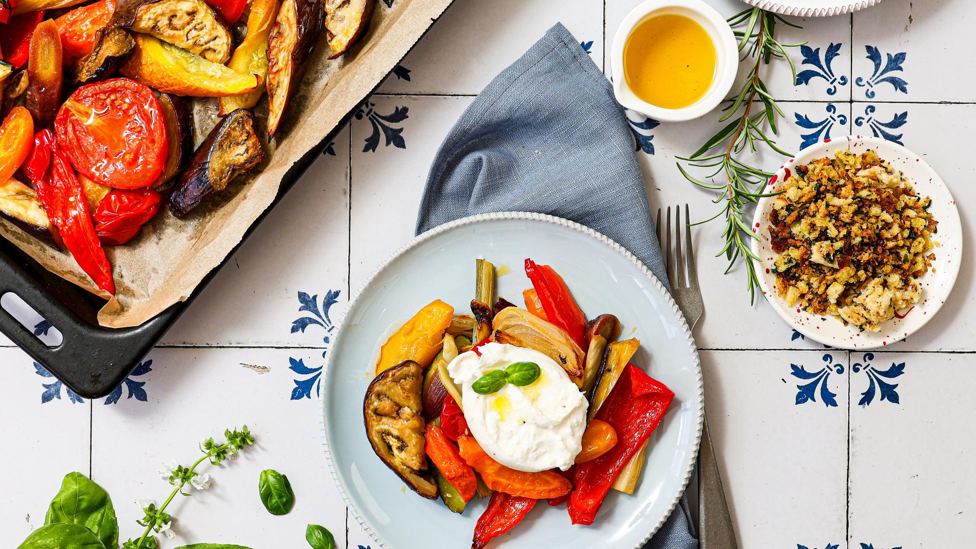 Ein Tisch mit einem Teller und Ofengemüse mit Burrata