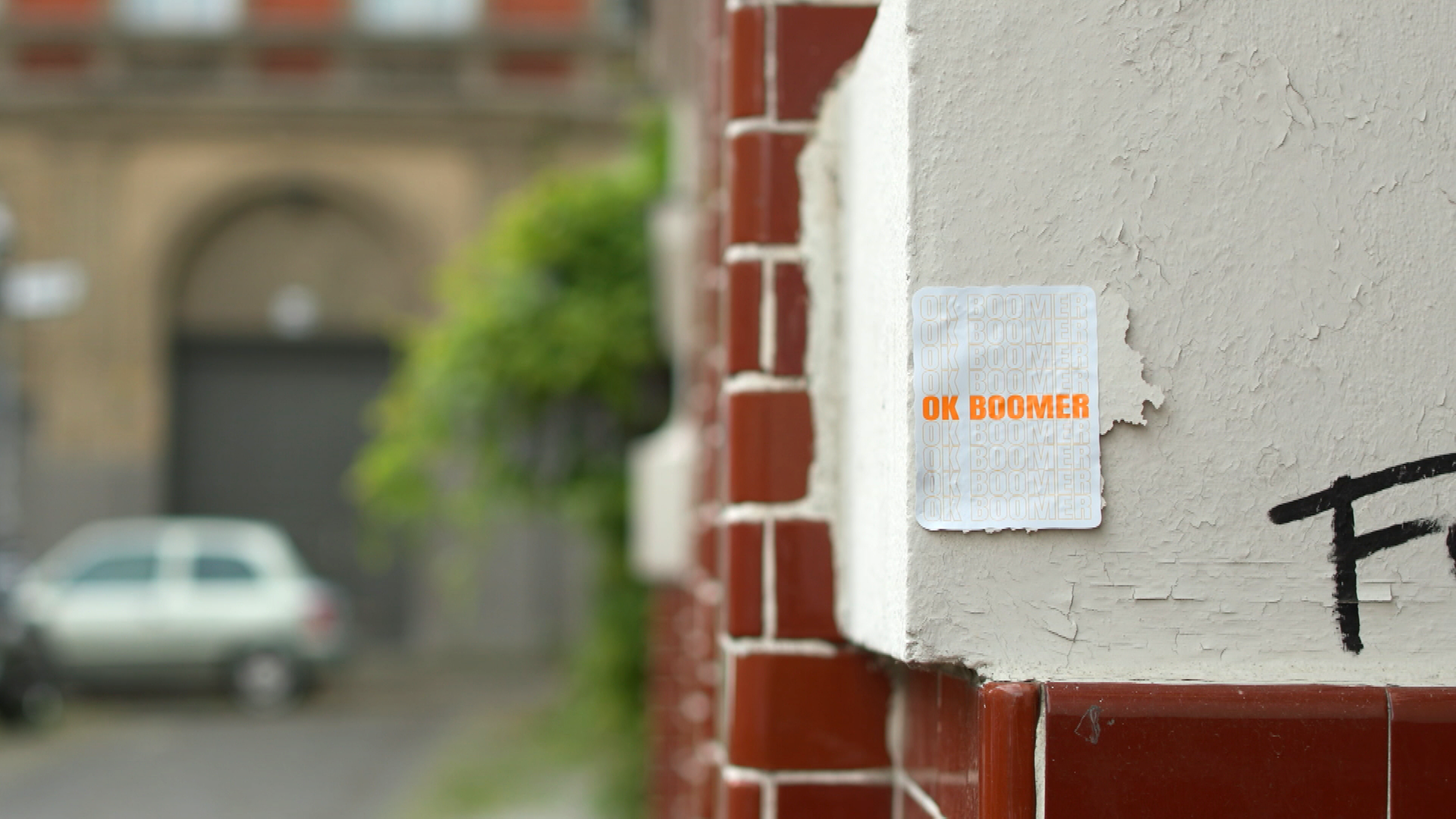Zettel mit Aufschrift "Ok Boomer" hängt an einer Hauswand