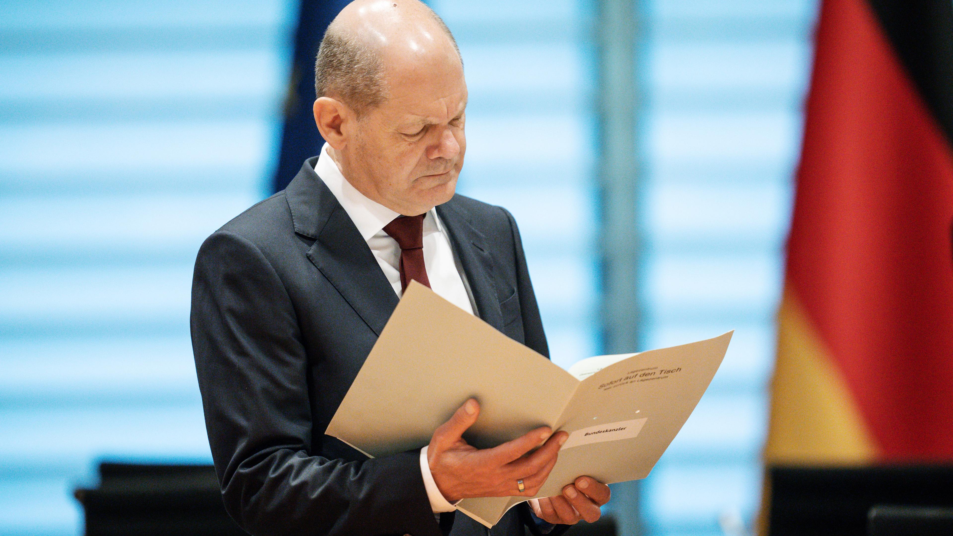Der Bundeskanzler Olaf Scholz liest in einer Akte.