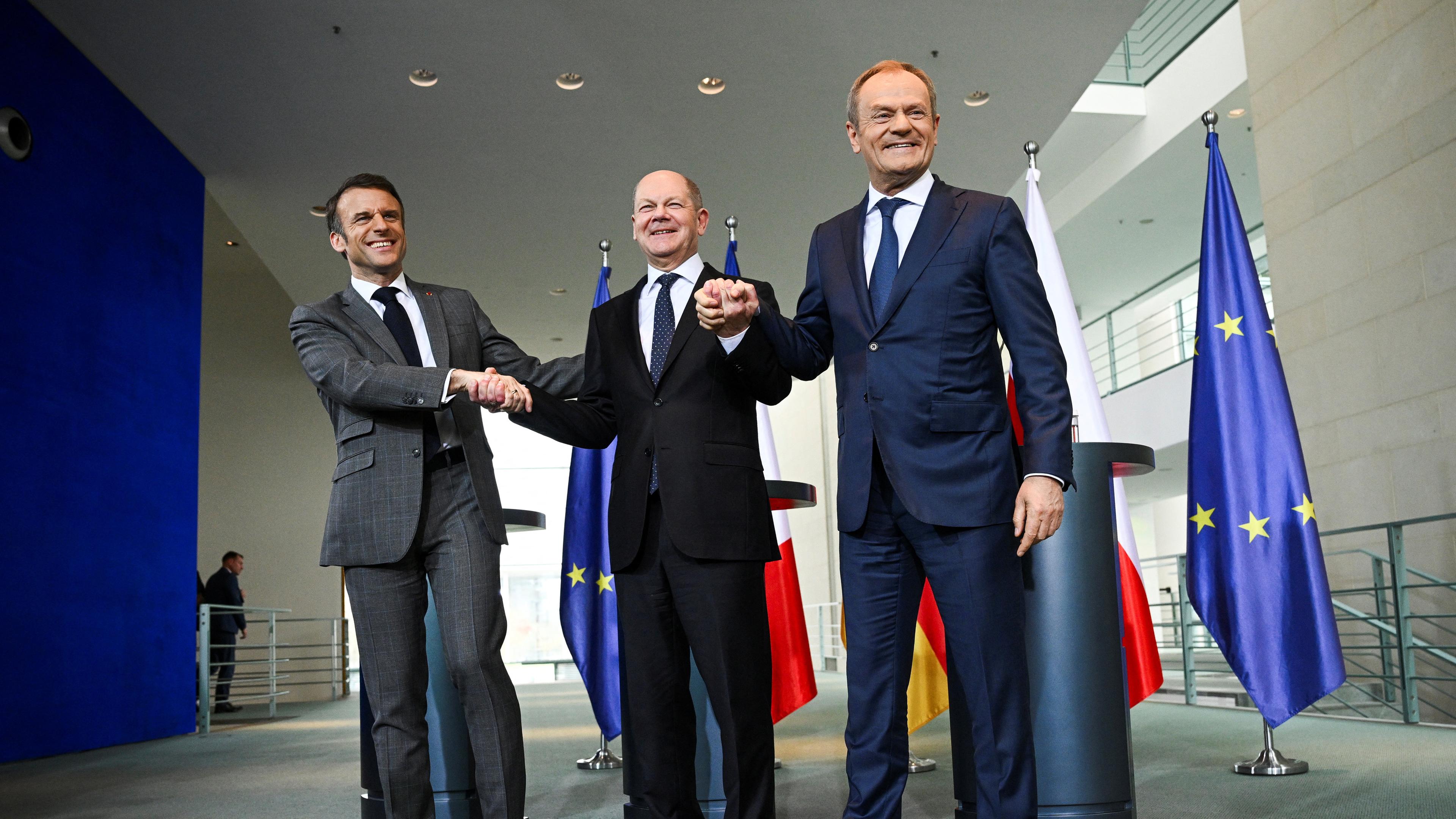 Olaf Scholz, Emmanuel Macron und Donald Tusk geben sich nach einer Presseerklärung vor ihrem trilateralen Treffen des Konsultationsforums "Weimarer Dreieck" im Kanzleramt in Berlin, 15.03.2024, die Hand.