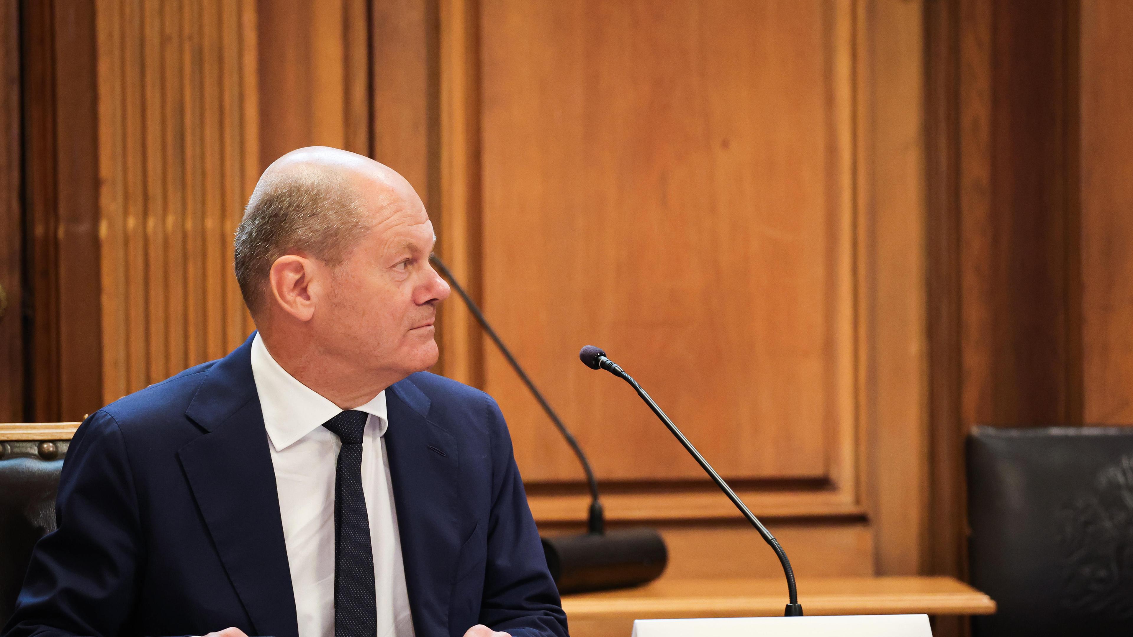 Archiv: Bundeskanzler Olaf Scholz (SPD) sitzt auf seinem Platz auf der Senatsbank mit einem Plastikschild mit dem Text ·Olaf Scholz Zeuge· vor Beginn einer Sitzung des Parlamentarischen Untersuchungsausschusses "Cum-Ex" im Plenarsaal der Hamburgischen Bürgerschaft im Rathaus. 