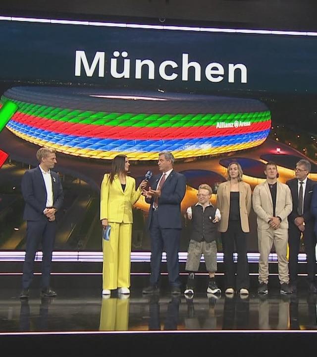 Auf der Bühne wird verkündet, dass München sich als Austragungsort für Olympia bewirbt.