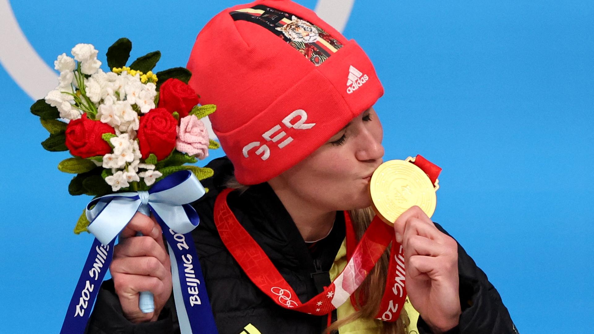 Natalie Geisenberger freut sich über ihren Sieg im Rennrodeln und küsst auf dem Podium ihre Goldmedaille.