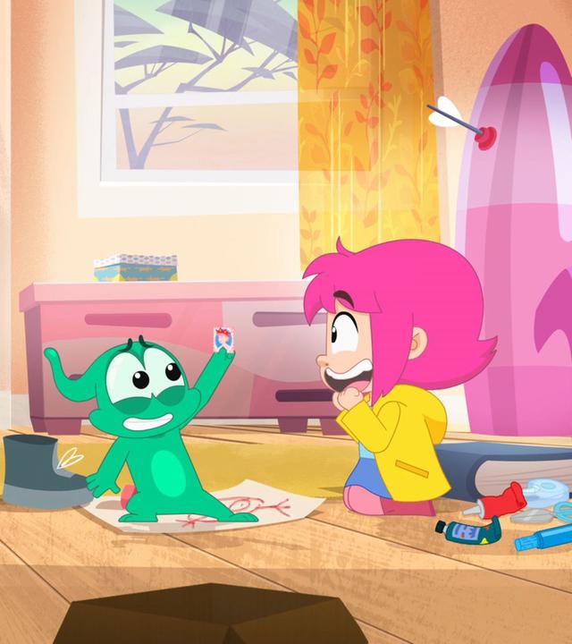 Ernest hält eine Briefmarke hoch und Rebecca schaut ihn begeistert an.