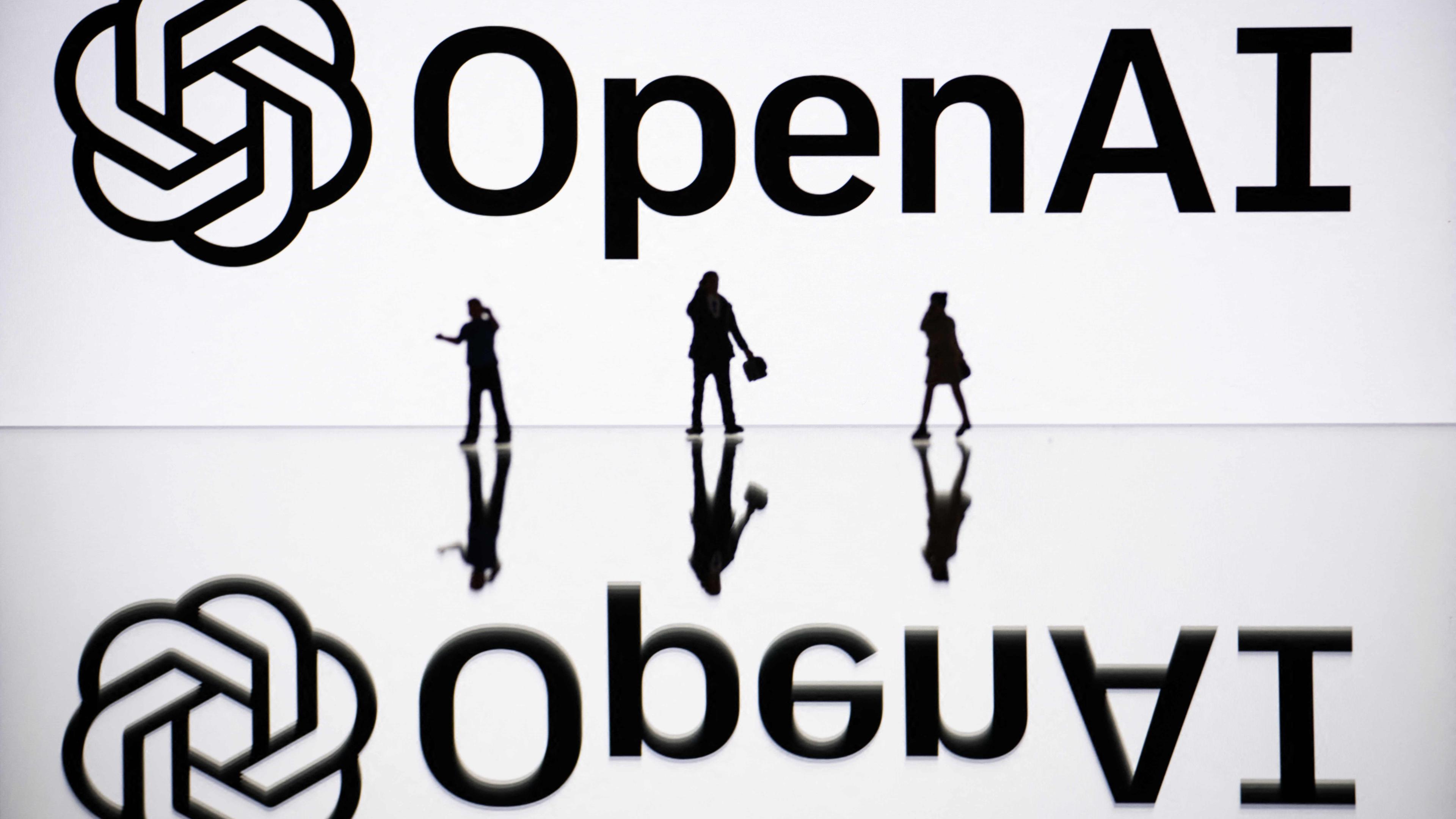 Symbolbild: Figuren neben einem Bildschirm, auf dem ein Logo von OpenAI