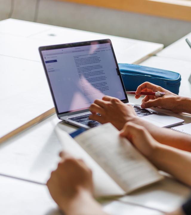 Schüler eines Gymnasiums sitzen vor einem Computer und benutzen ein KI-Tool.