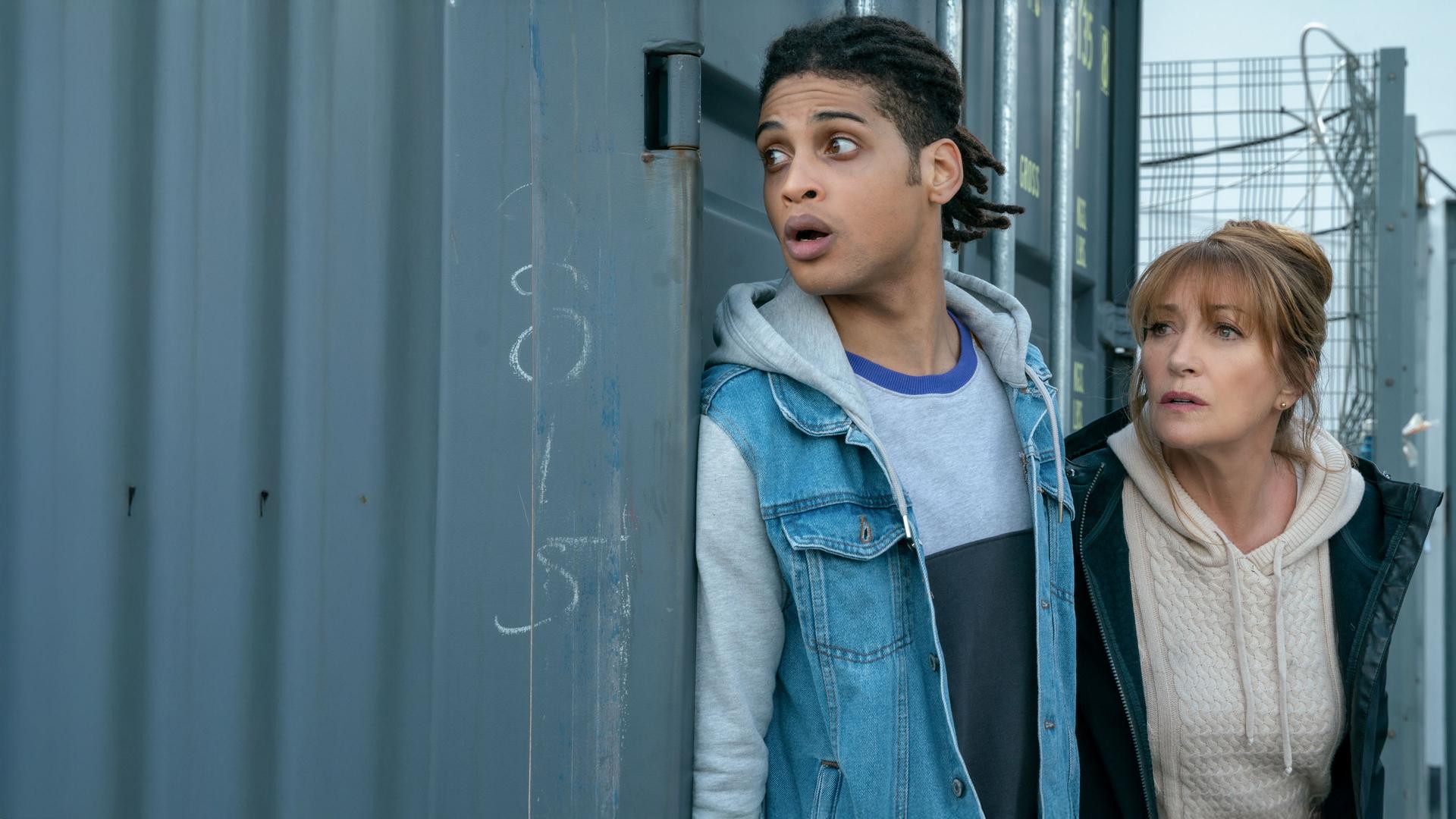 "Harry Wild - Mörderjagd in Dublin: Operation Mincemeat": Harry Wild (Jane Seymour) und Fergus Reid (Rohan Nedd) verstecken sich hinter einem grauen Container.