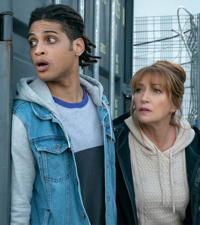 "Harry Wild - Mörderjagd in Dublin: Operation Mincemeat": Harry Wild (Jane Seymour) und Fergus Reid (Rohan Nedd) verstecken sich hinter einem grauen Container.