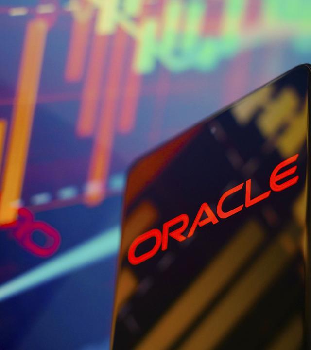 Auf einem Smartphone ist in Rot auf Schwarz das Wort Oracle zu sehen. Im Hintergrund sind bunte digitale Schemata zu sehen.