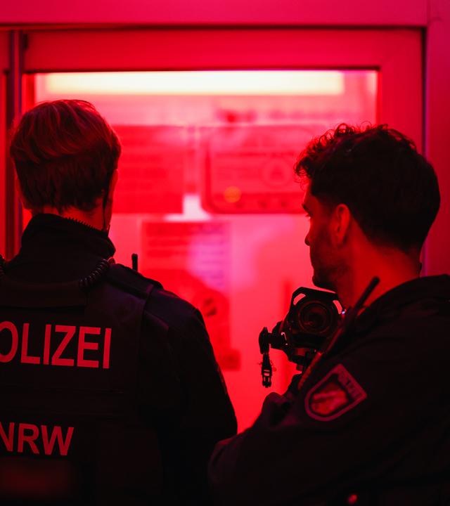 Zwei Polizisten (von hinten zu sehen) bei einem Einsatz