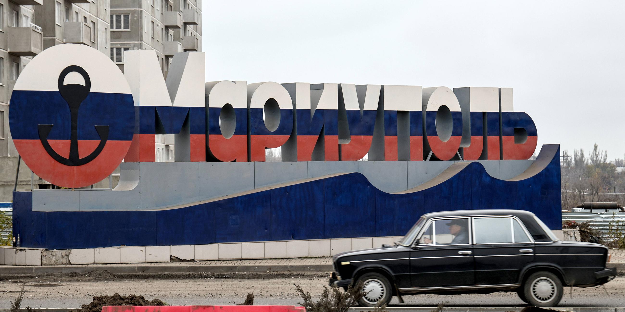 Archiv: Auto steht vor einem Willkommensschild in den Farben der russischen Flagge in Mariupol. (11.11.2022)