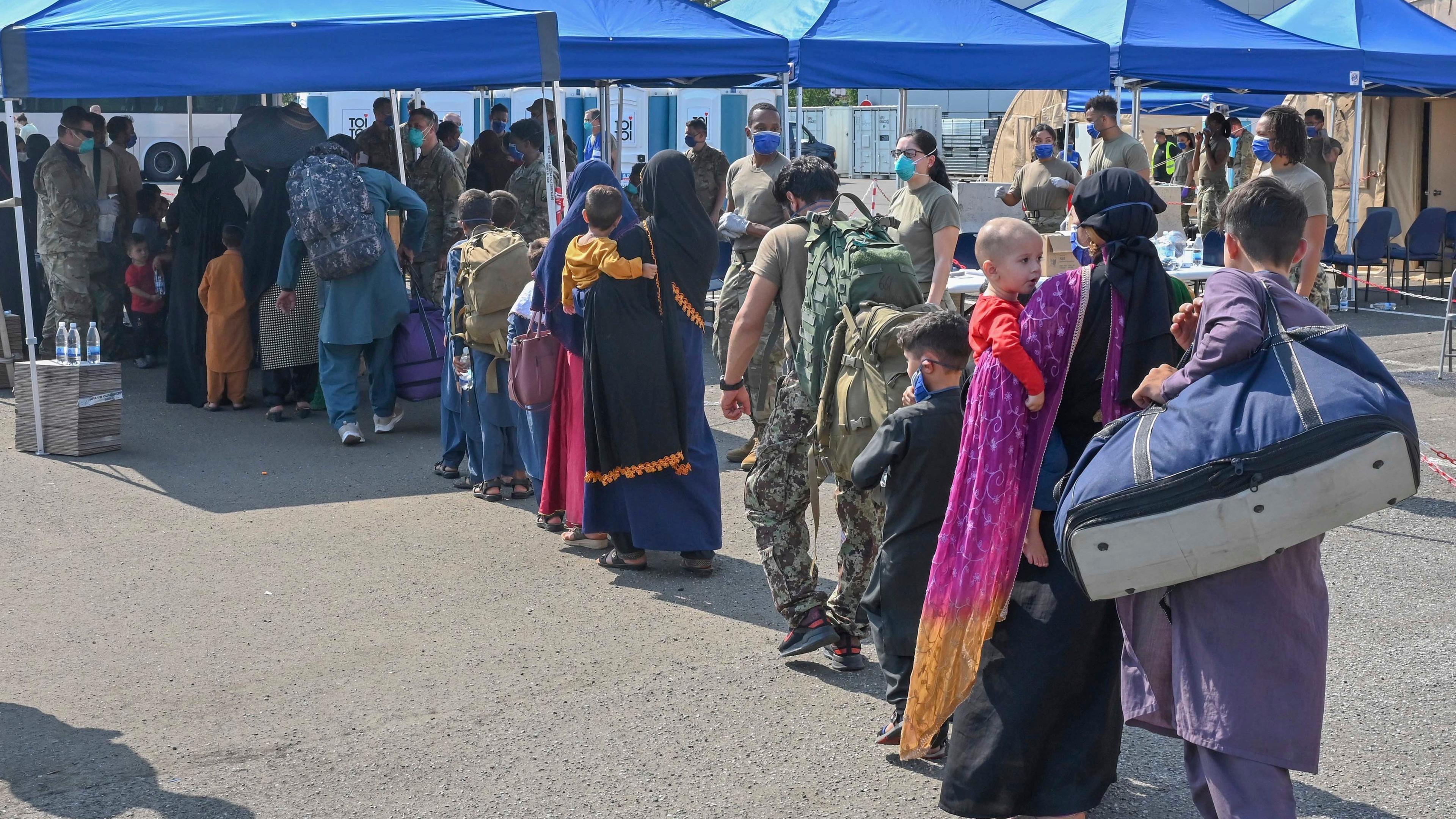 Afghanische Flüchtlinge, die aus Kabul evakuiert wurden, stellen sich nach ihrer Ankunft auf der Air Base Ramstein zur Abfertigung auf. 