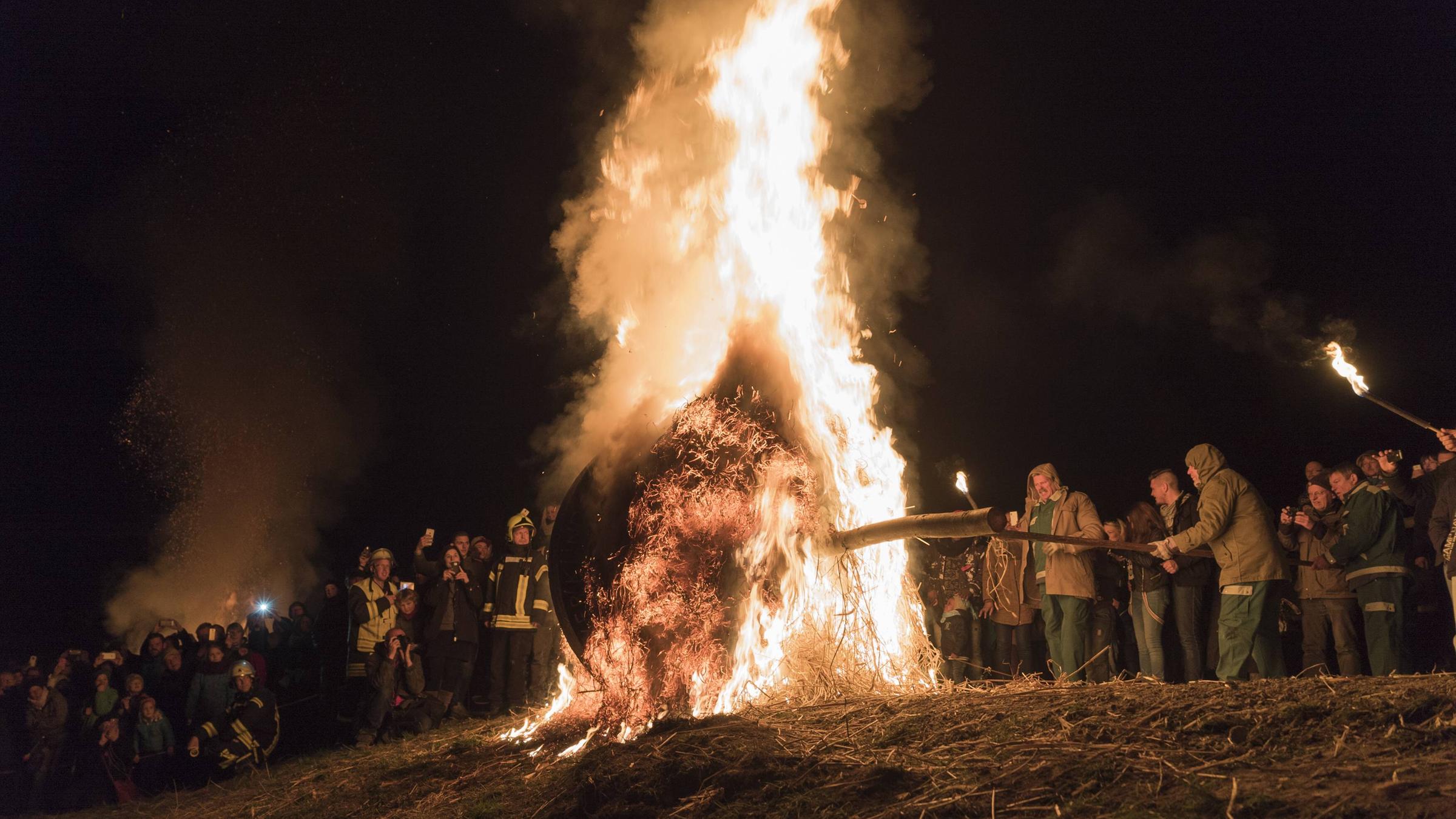 Mit Stroh gefülltes Rad wird angezündet und einen Berg hinunter gerollt.