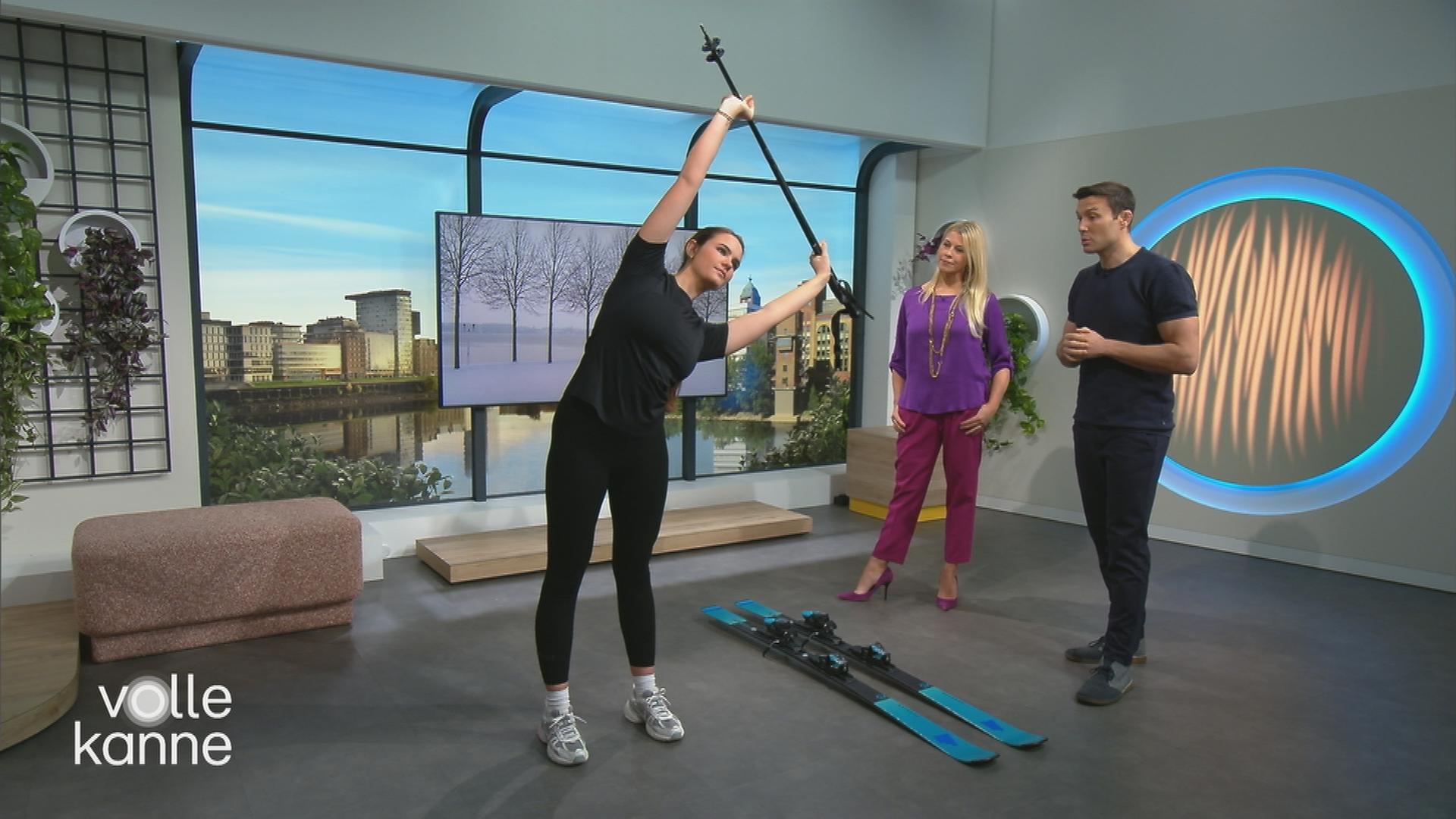 Drei Personen stehen im Studio, eine macht Sportübungen