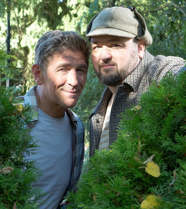 Fritz und David schauen durch eine Hecke