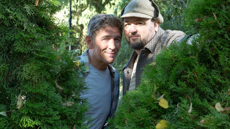 Fritz und David schauen durch eine Hecke