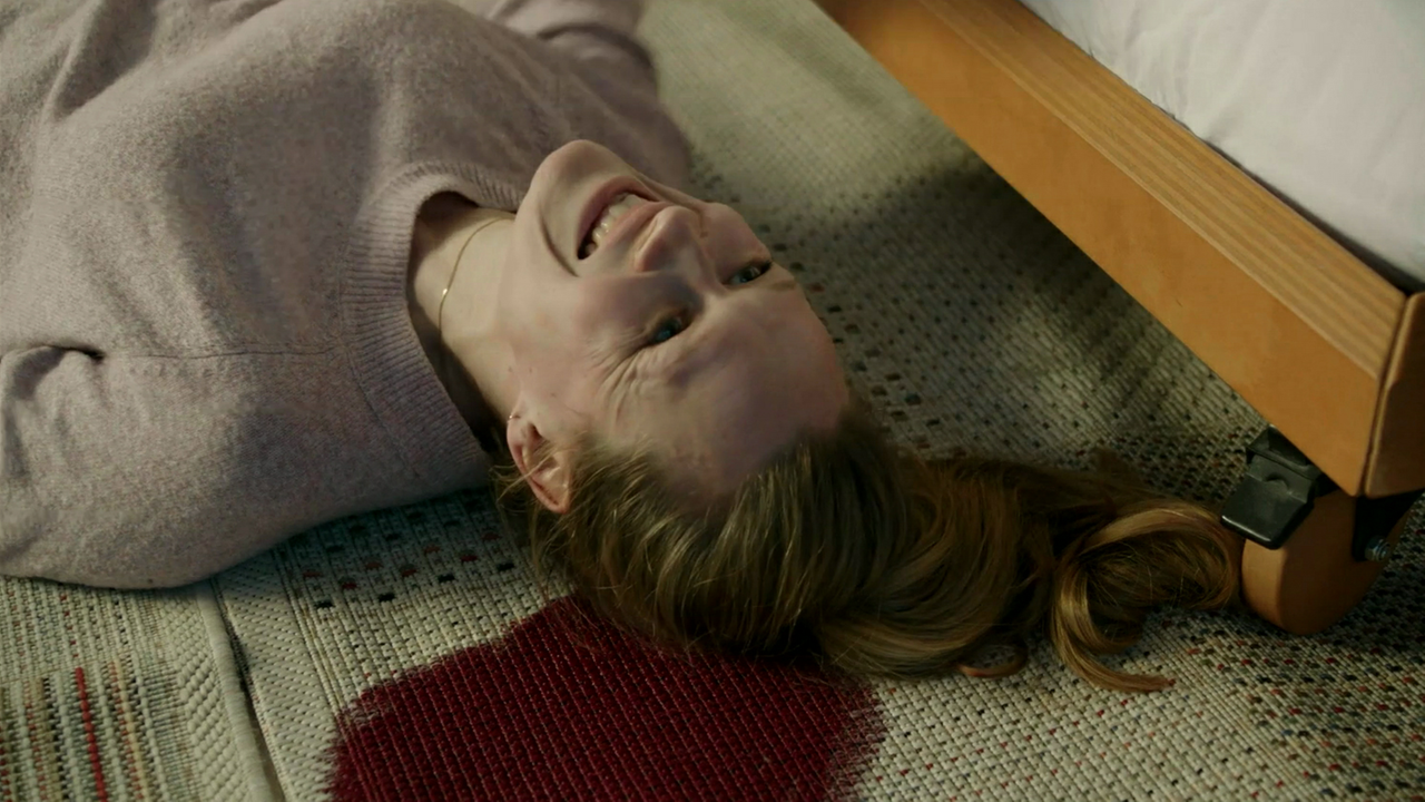 Eine Schauspielerin, die eigentlich eine Leiche spielt, liegt lachend auf dem Boden