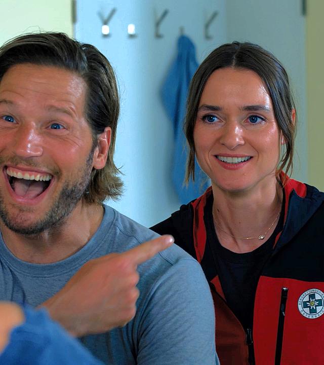 Sebastian Ströber zeigt lachend auf Frau neben sich.