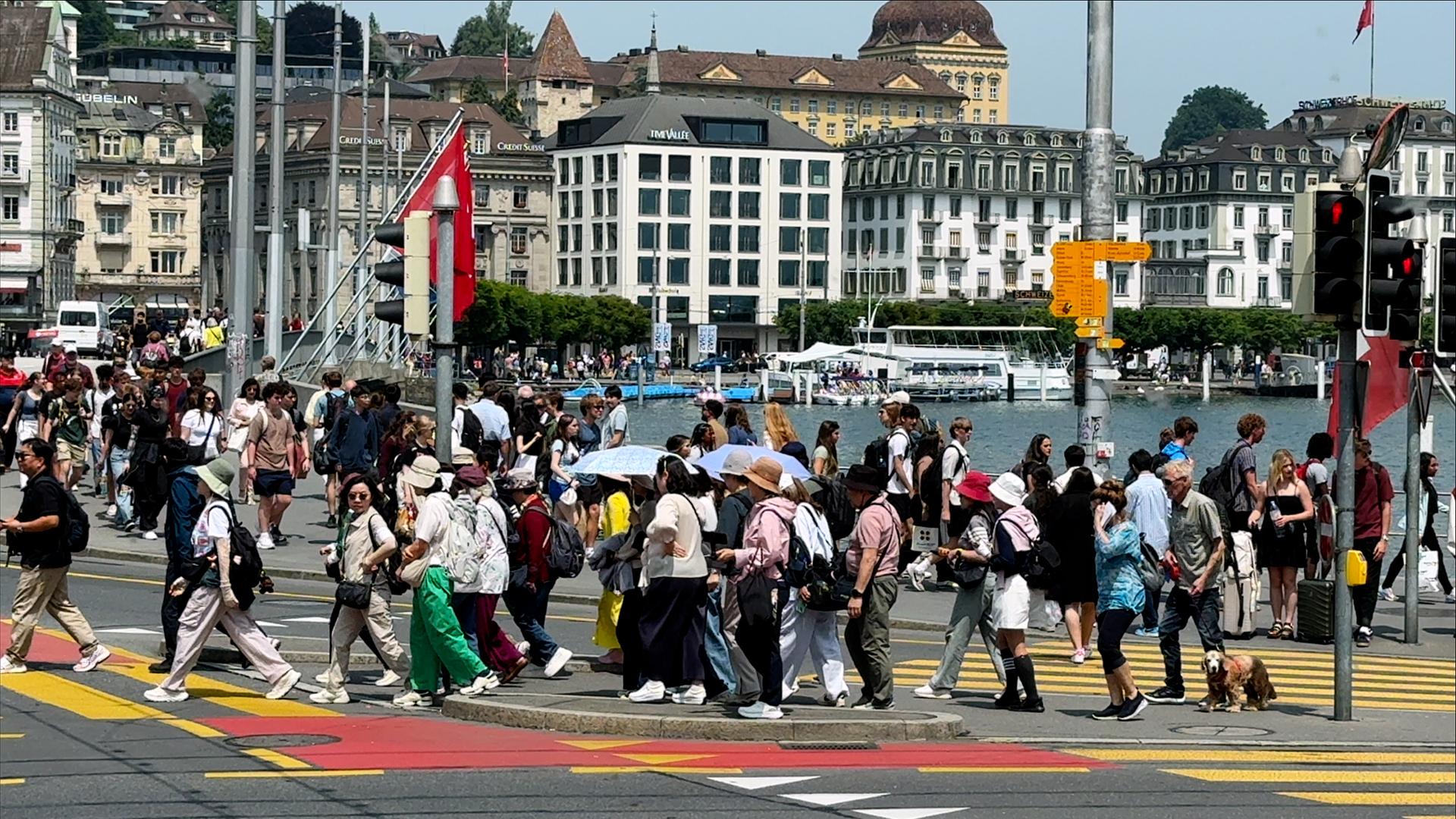 Viele Menschen laufen über einen Fußgängerweg einer Straße am Wasser.