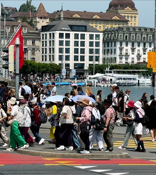 Viele Menschen laufen über einen Fußgängerweg einer Straße am Wasser.