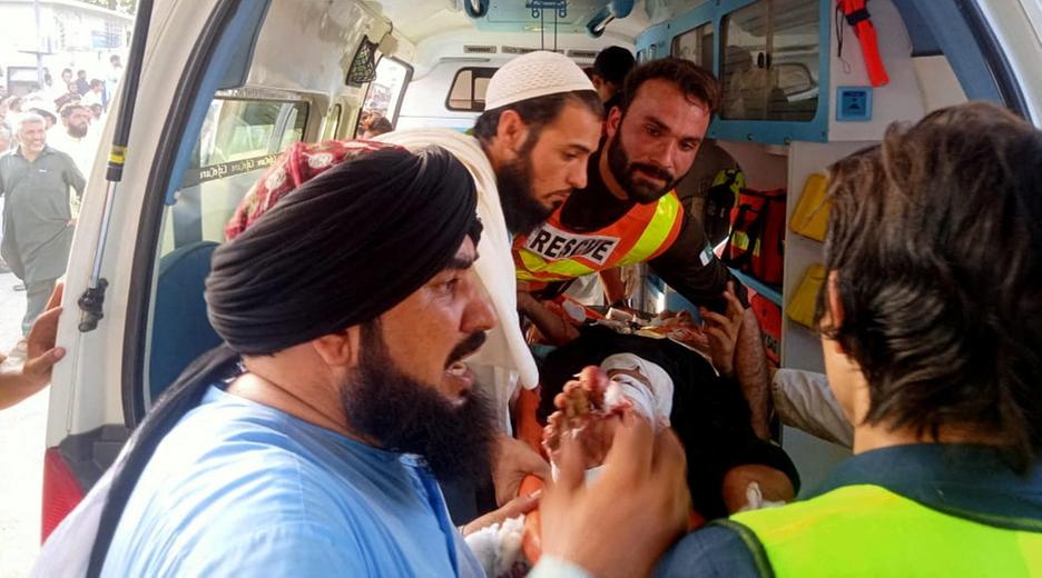 Pakistanische Rettungskräfte behandeln eine verletzte Person nach einem Anschlag auf einer Veranstaltung einer islamistischen Partei