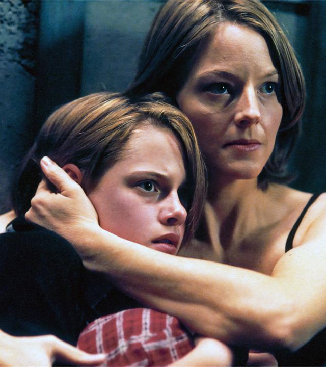 "Panic Room": Meg (Jodie Foster) hält Sarah (Kristen Stewart) fest in den Armen und blickt angespannt zur Seite. Beide sitzen dicht vor einer Betonwand.