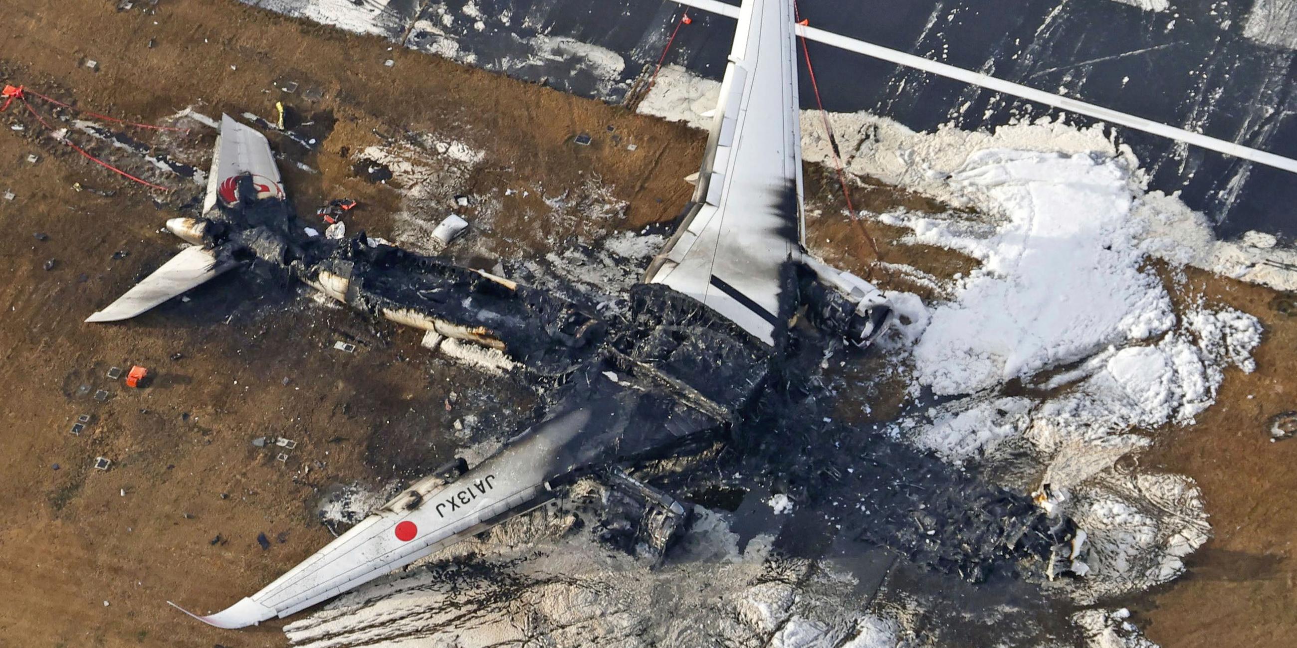 Japan, Tokio: Die Luftaufnahme zeigt das ausgebrannte Flugzeug der Japan Airlines auf dem Flughafen Haneda. 