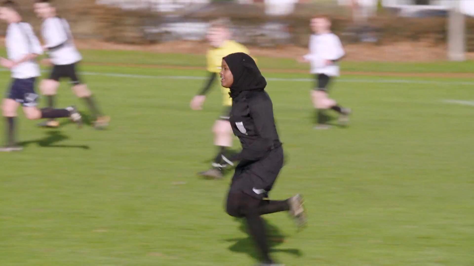 Die muslimische Schiedsrichterin pfeift ein Fußballspiel. Auf dem Bild läuft sie den anderen Spielern hinterher.