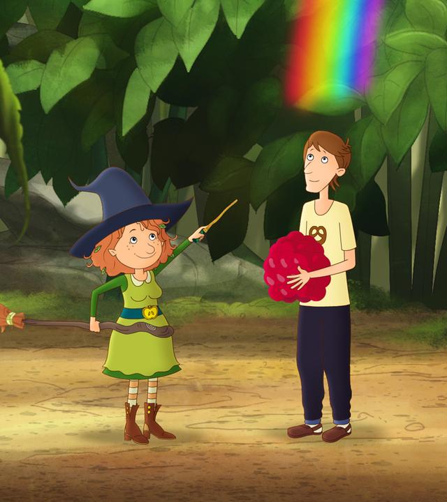 Papa Paul steht mit einer Himbeere in seinen Arme im magischen Garten. Neben ihm schwingt Petronella Apfelmus einen Zauberstab. Über ihm sind Regenbogenfarben.