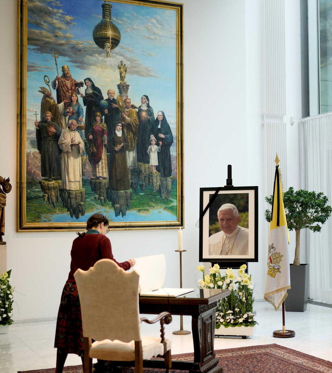 Eine Frau legt das Kondolenzbuch für den verstorbenen emeritierten Papst Benedikt XVI. in der Botschaft des Vatikans in Berlin, aufgenommen am 02.01.2023