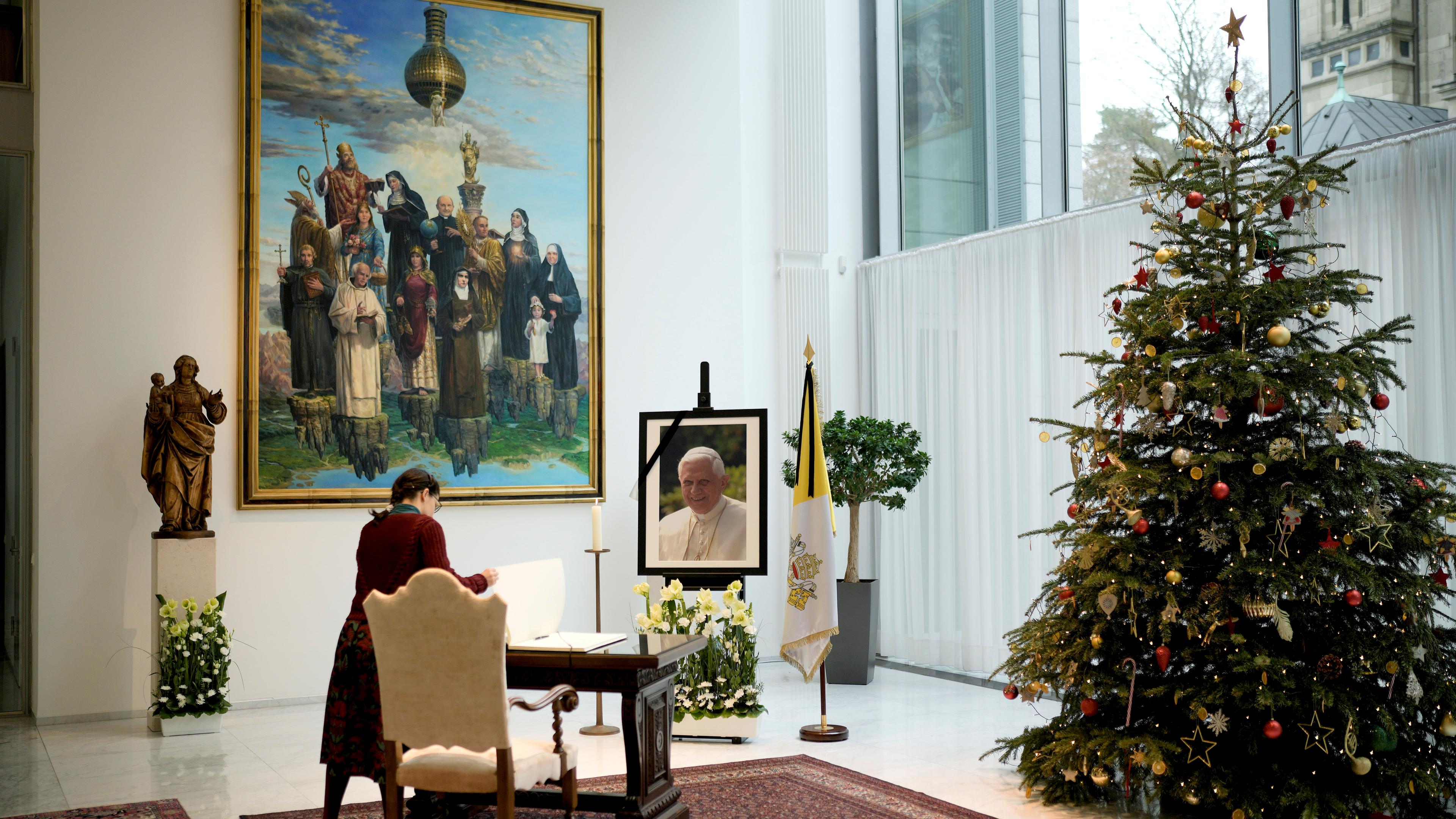 Eine Frau legt das Kondolenzbuch für den verstorbenen emeritierten Papst Benedikt XVI. in der Botschaft des Vatikans in Berlin, aufgenommen am 02.01.2023