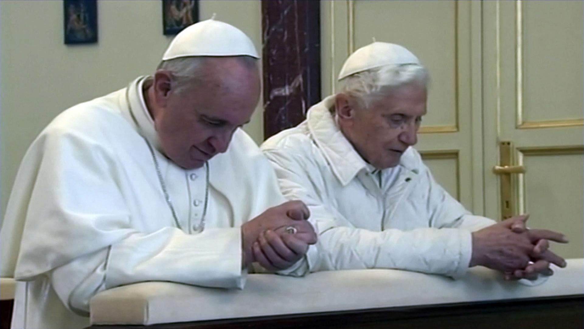 Papst Benedikt XVI. und Papst Franziskus kniend beim Gebet und haben beide weiße Gewänder an