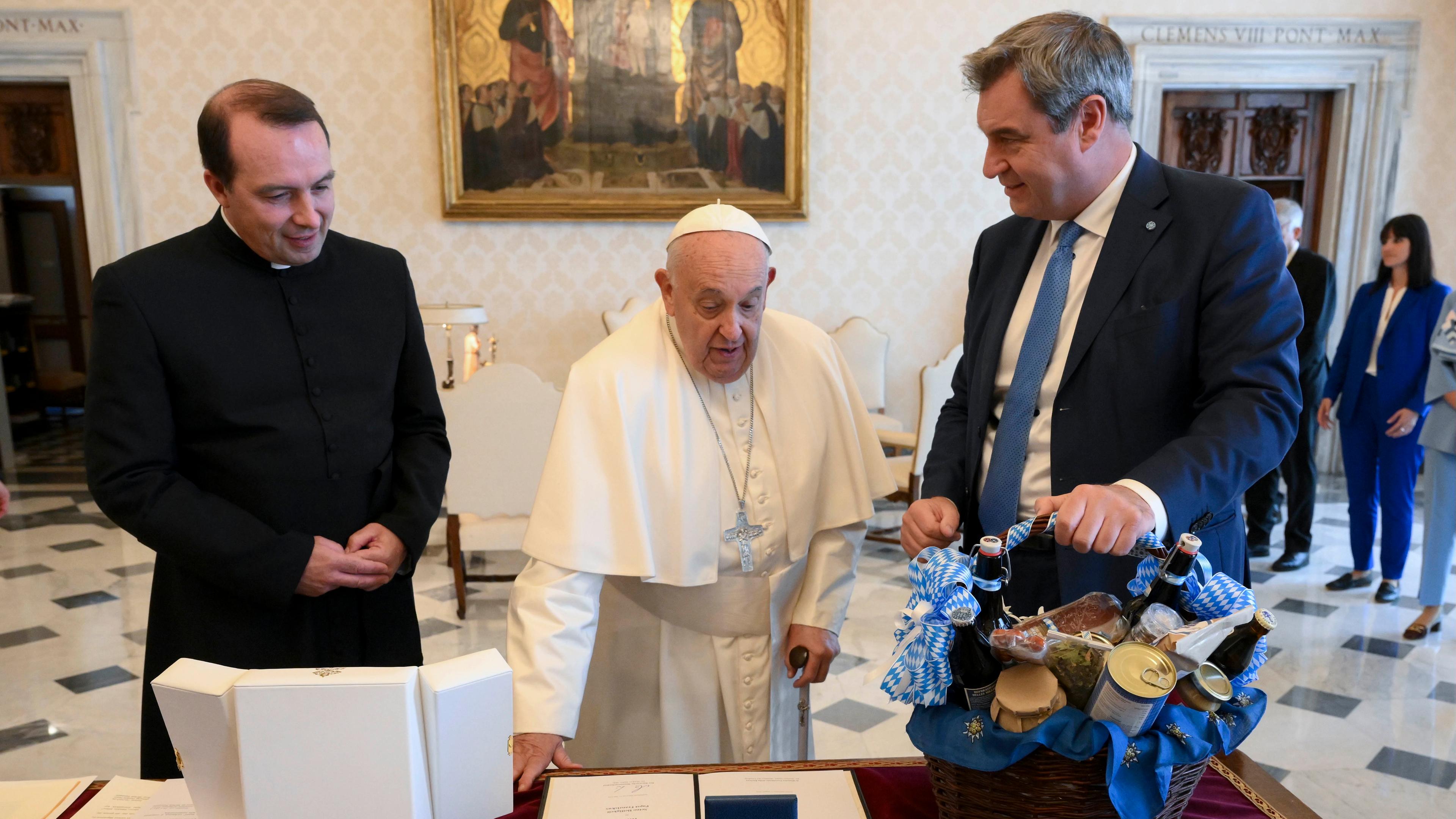 Italien, Rom: Bayerns Ministerpräsident Markus Söder (CDU, r) und Johannes Palus (l), Priester der Erzdiözese München und Freising, übergeben bei einer Privataudienz dem Papst Franziskus Geschenke. 