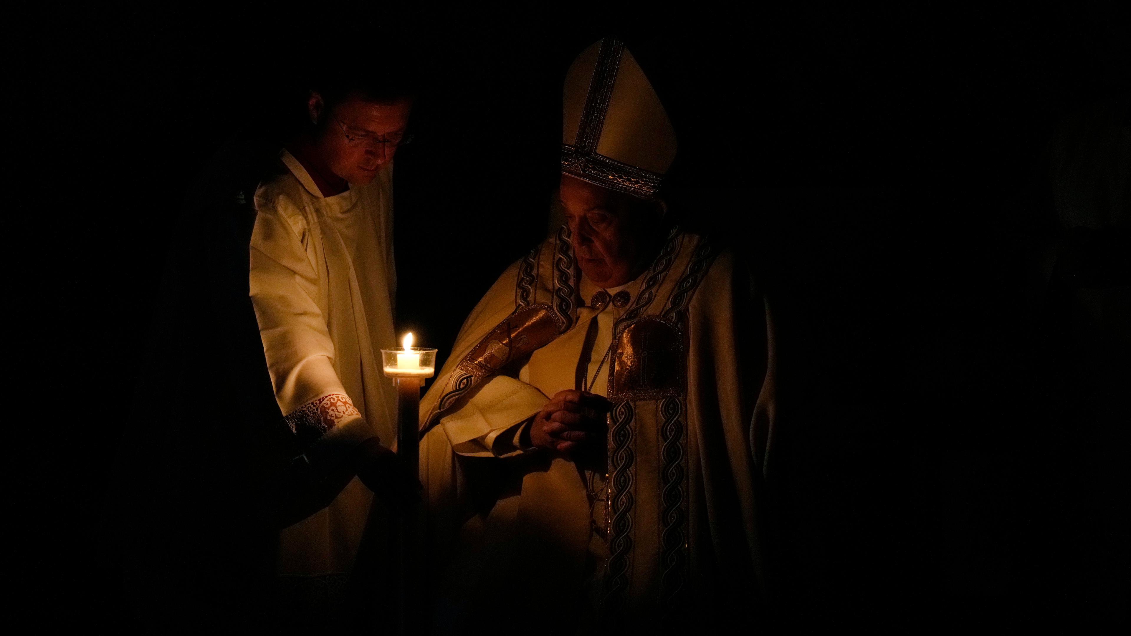 Papst Franziskus sitzt im Schein einer Kerze während der Osternacht im Petersdom. 