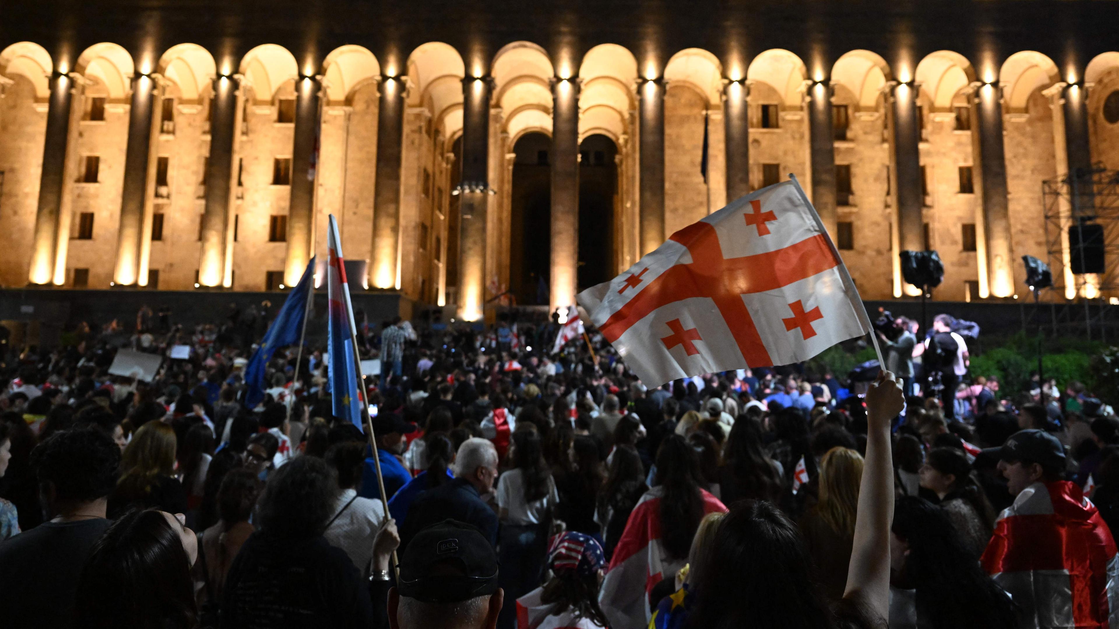 Demonstranten halten eine georgische Flagge und Plakate während einer Kundgebung vor dem georgischen Parlament, um gegen ein umstrittenes Gesetz über "ausländische Einflussnahme" zu protestieren, das laut Brüssel die europäischen Bestrebungen Georgiens untergraben würde, in Tiflis am 02.05.2024. 