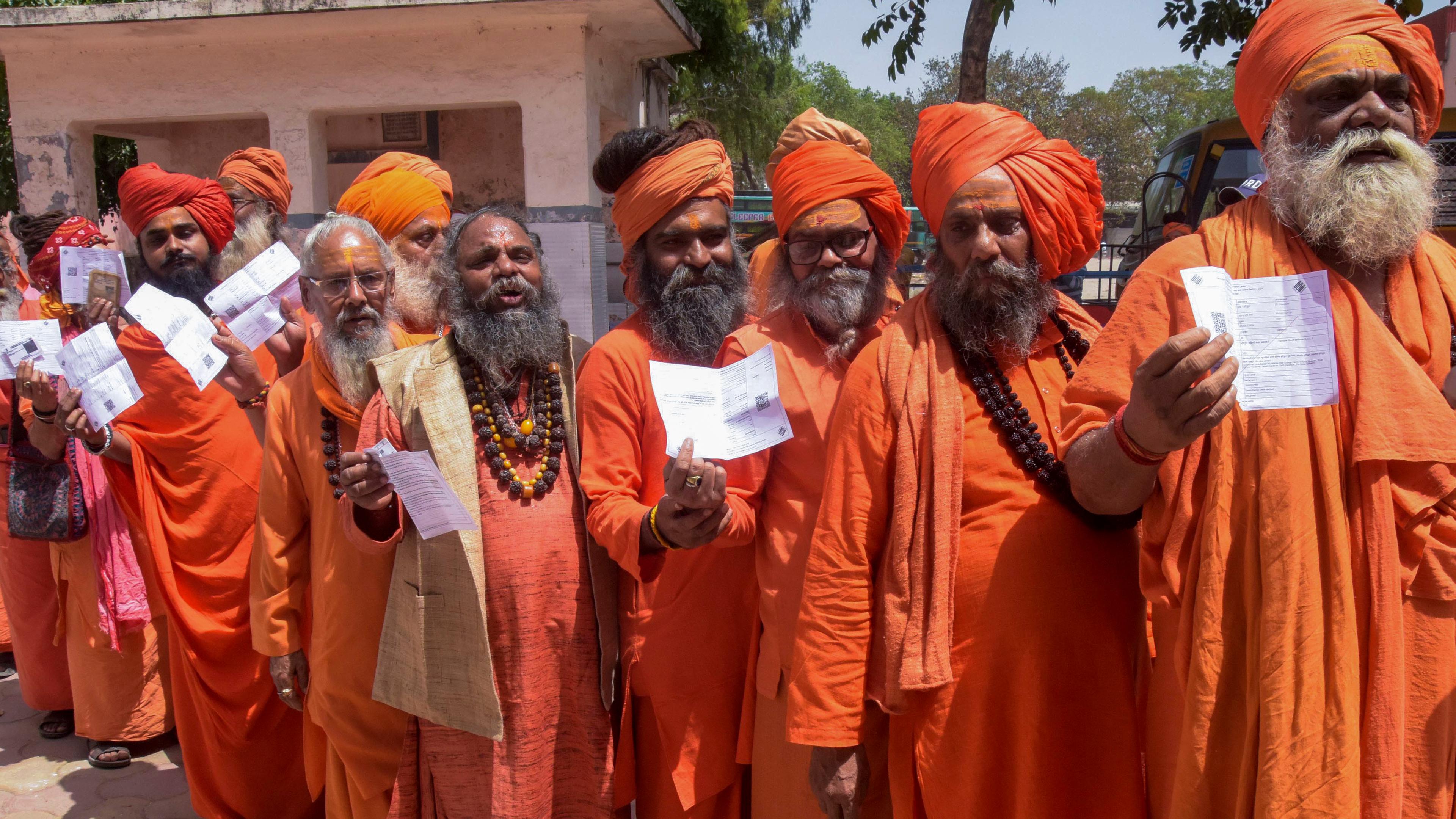 induistische Heilige in safranfarbenen Gewändern stehen Schlange, um ihre Stimme während des ersten Wahlgangs der indischen Parlamentswahlen in Haridwar abzugeben.