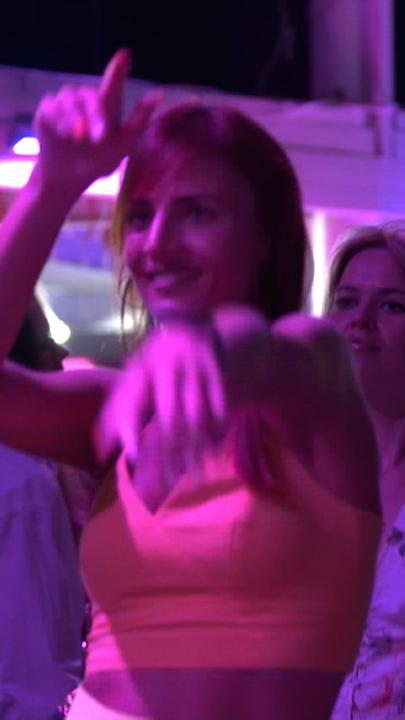 Ein junges Mädchen steht auf der Tanzfläche eines Club, in dem blaues und lilanes Licht leuchten