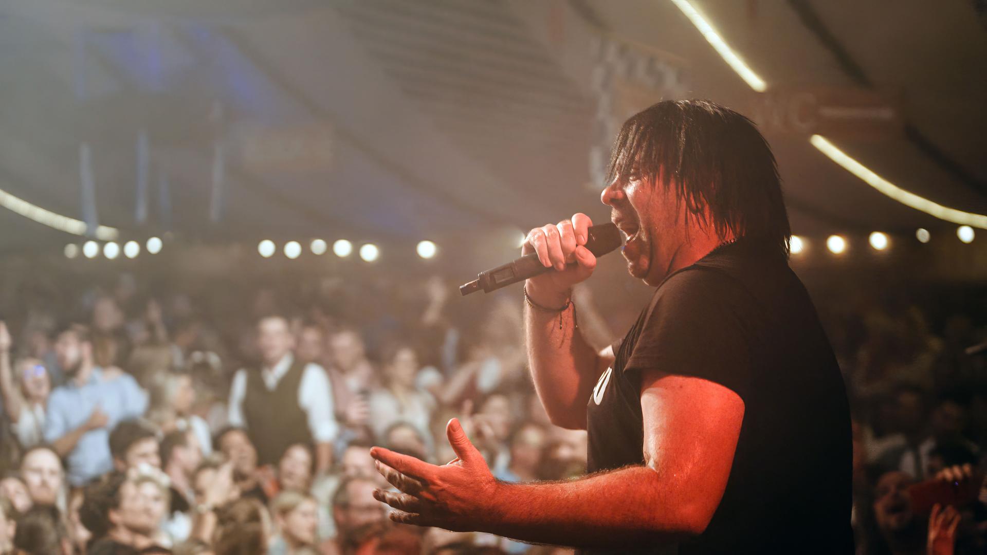 Ikke Hüftgold singt vor Publikum auf einer Bühne bei einem Dorffest.