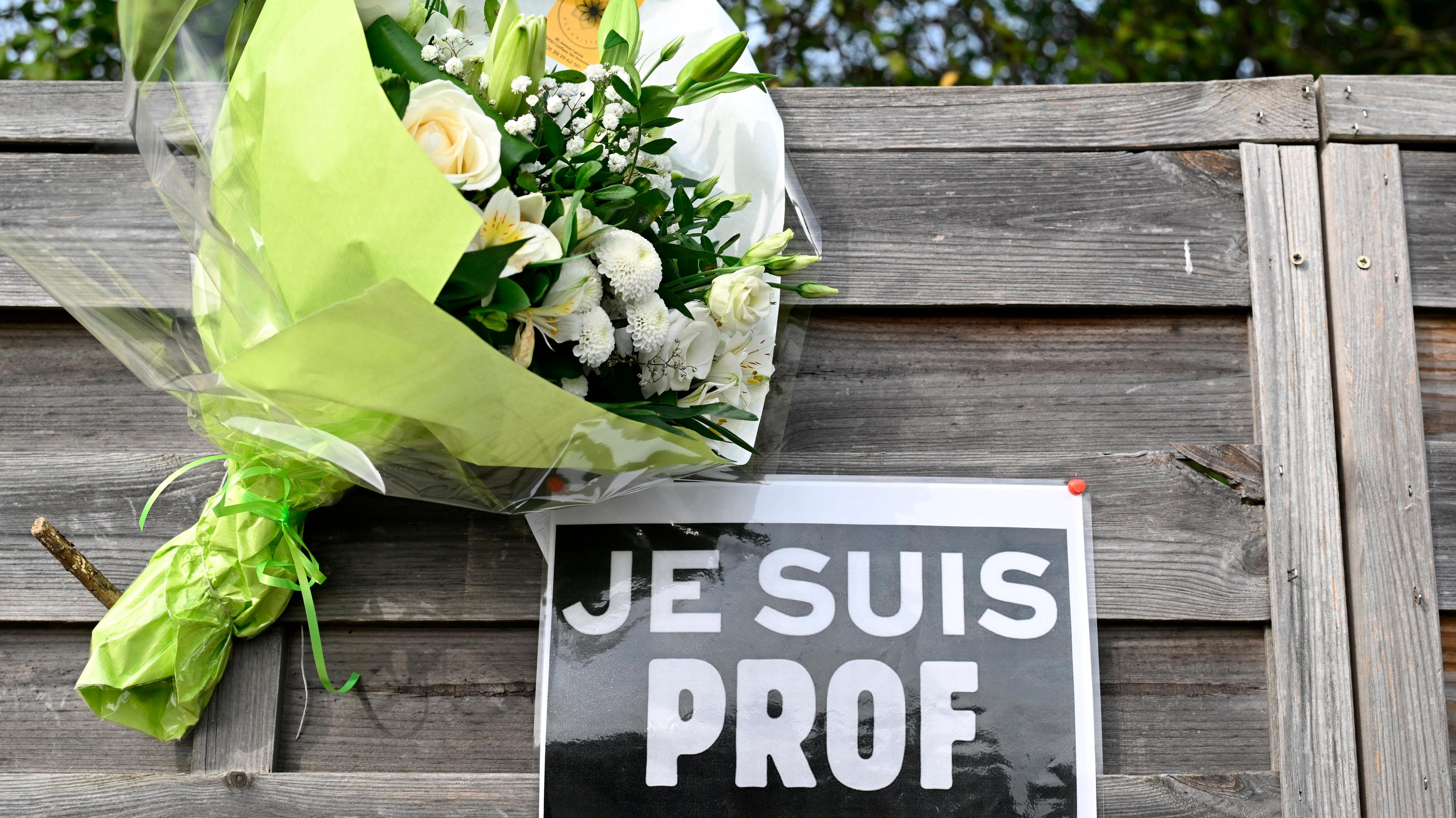 Ein Blumenstrauß sowie ein Zettel mit der Aufschrift "Je suis Prof" (Ich bin Lehrer) zum Gedenken an den ermordeten Lehrer Samuel Paty.
