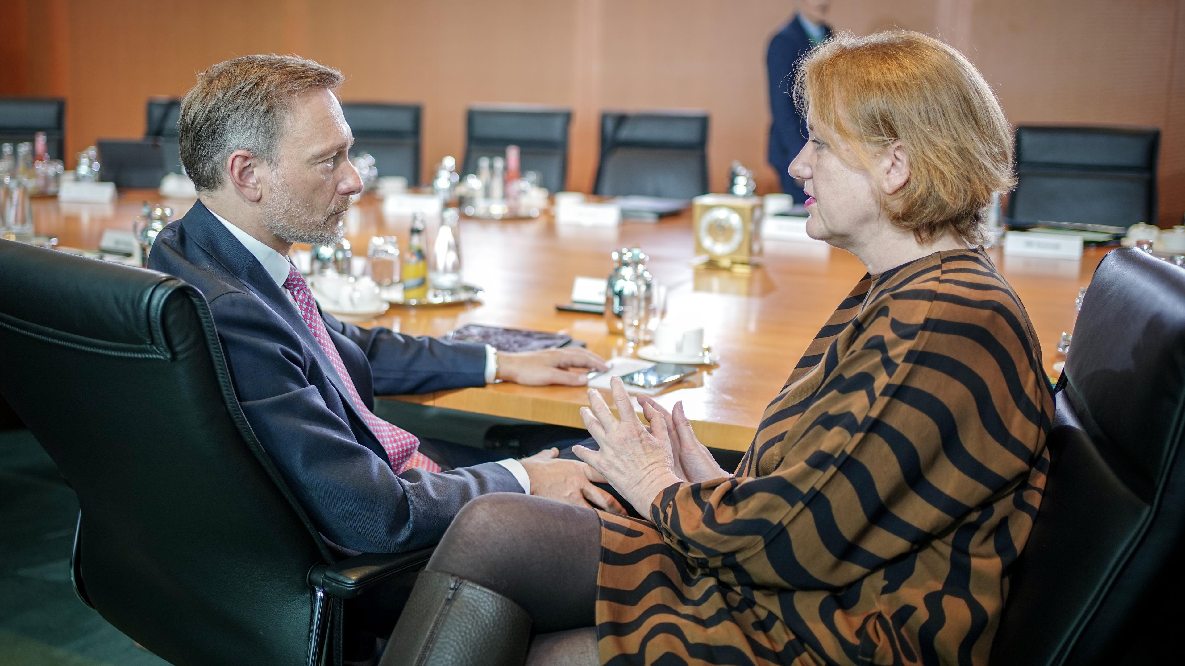 Finanzminister Christian Lindner und Bundesfamilienministerin Lisa Paus sind sitzend im Profil zu sehen. Sie unterhalten sich an einem Konferenztisch.
